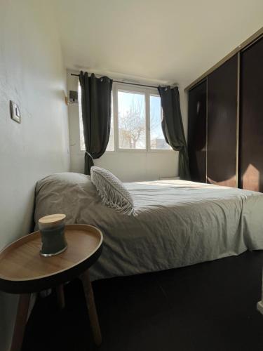 Appart au pied du T2 La Défense Paris في بيزونس: غرفة نوم بسرير مع طاولة ونافذة