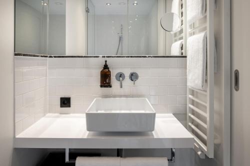 a white bathroom with a sink and a mirror at Hotel AMANO Grand Central in Berlin