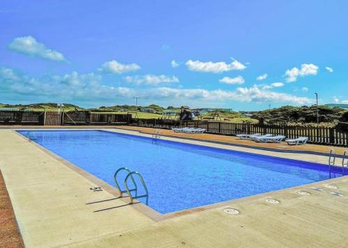 a large blue swimming pool with chairs in the background at Burrowhead Holiday Village in Isle of Whithorn