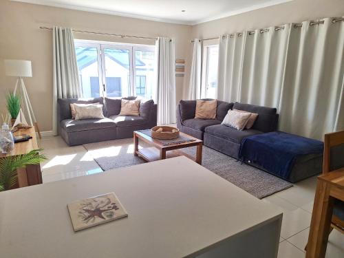 a living room with two couches and a table at Waves Edge at 14 Bridge Waters in Jeffreys Bay