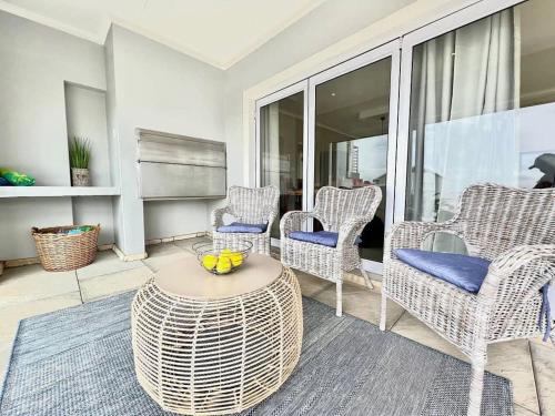 a living room with wicker chairs and a table at Waves Edge at 14 Bridge Waters in Jeffreys Bay