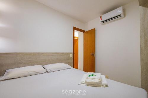 a bedroom with a white bed with towels on it at Condomínio no litoral em Imbassaí - SOV in Imbassai