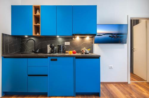 a blue kitchen with black counter tops and blue cabinets at D&A Central Luxury Apartments with FREE Parking in Pula