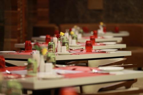 a row of tables with red napkins and white plates at Hotel Park Elanza Chennai in Chennai