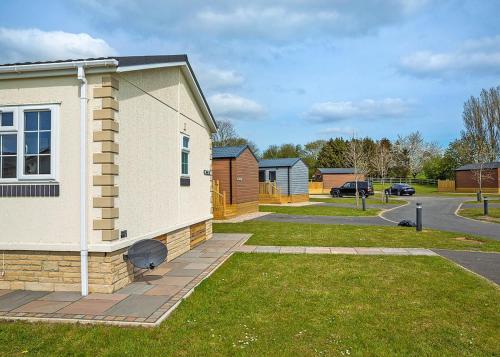 a house with a grass yard next to a street at Cleveland Hills View Holiday Park in Middleton upon Leven