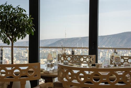 a table with wine glasses and a view of a city at Panorama Lisi Grand Hotel in Tbilisi City
