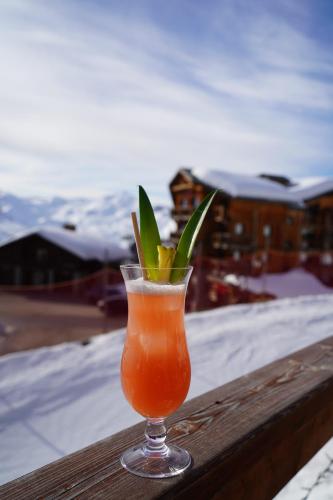 a drink in a glass sitting on a wooden rail at Hôtel Le Sherpa Val Thorens in Val Thorens