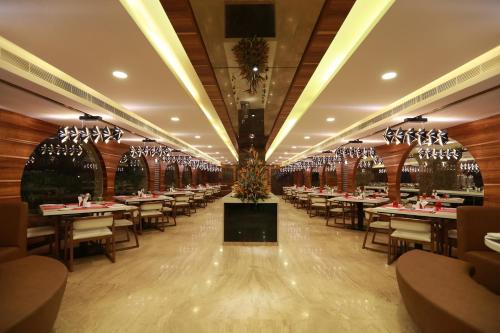 a dining room with tables and chairs and chandeliers at Hotel Park Elanza Chennai in Chennai