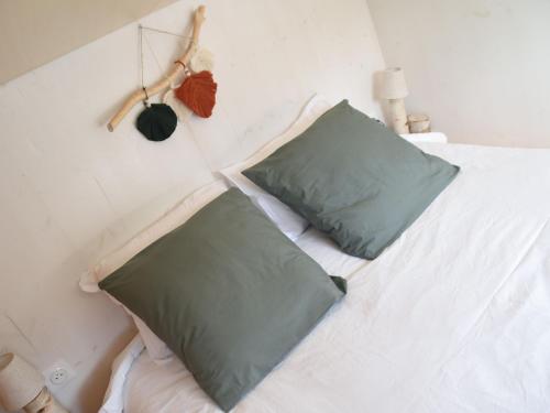 a white bed with two green pillows on it at Charmante tiny house avec baie extérieure et kota grill à Manoncourt-en-Vermois - FR-1-584-374 in Manoncourt-en-Vermois
