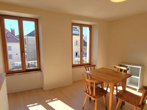 une salle à manger avec une table, des chaises et des fenêtres dans l'établissement Appartement T2 rénové - 2 pers - Centre St Bonnet - FR-1-393-180, à Saint-Bonnet-en-Champsaur