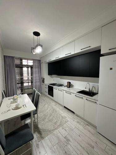 a kitchen with white cabinets and a table and a dining room at Nazz in Bishkek