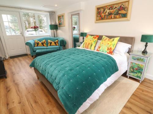 a bedroom with a large bed with a green comforter at Elder Cottage Studio in Truro