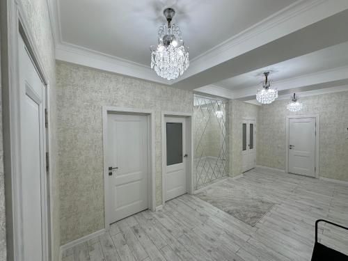 an empty room with a chandelier and a hallway at Nazz in Bishkek