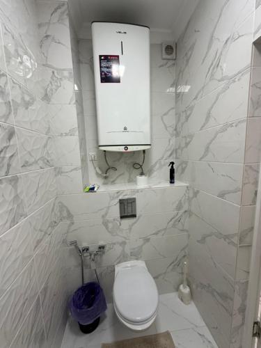a white bathroom with a toilet and a cabinet at Nazz in Bishkek