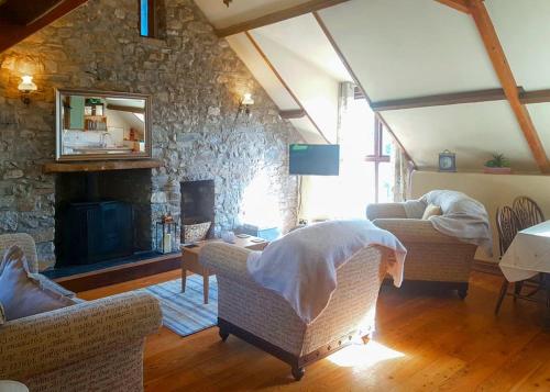 a living room with couches and a stone fireplace at Garnffrwd Cottages in Llanddarog