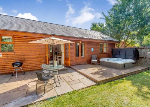 eine Terrasse mit Tisch und Sonnenschirm in der Unterkunft Ford Farm Lodges in Aston Ingham