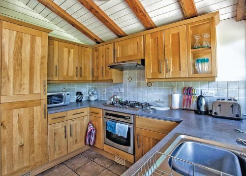 a kitchen with wooden cabinets and a sink at Great Wood Lodges in Flaxton