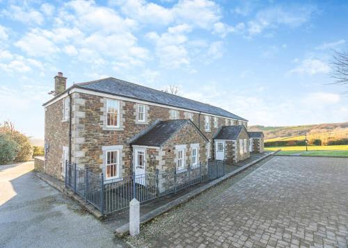 a large brick building with a fence in front of it at Green Acres Cottages in Par