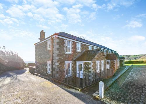 ein altes Backsteingebäude mit einem Zaun davor in der Unterkunft Green Acres Cottages in Par