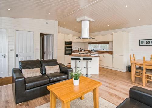 a living room with a black leather couch and a table at Warren Lodges in Little Baddow