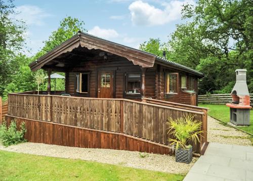 a log cabin with a wooden fence in a yard at Heronstone Lodges in Ystalyfera