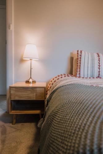 a bedroom with a bed and a lamp on a night stand at Retreat, Relax, Repeat in Katoomba, Blue Mountains in Katoomba