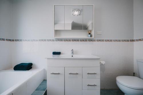 a white bathroom with a toilet and a sink at Retreat, Relax, Repeat in Katoomba, Blue Mountains in Katoomba