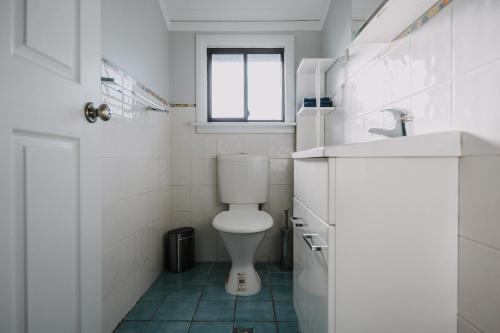 a white bathroom with a toilet and a window at Retreat, Relax, Repeat in Katoomba, Blue Mountains in Katoomba