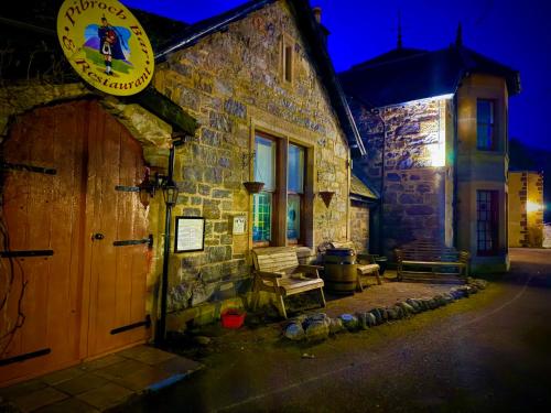 a stone building with a wooden door and a bench at Loch Ness Lodge Hotel in Drumnadrochit