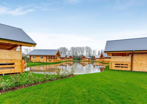 a river with some wooden buildings and a pond at Holly Tree Lodges in York