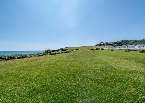 a field of green grass with a building in the background at Ladram Bay Holiday Park in Otterton