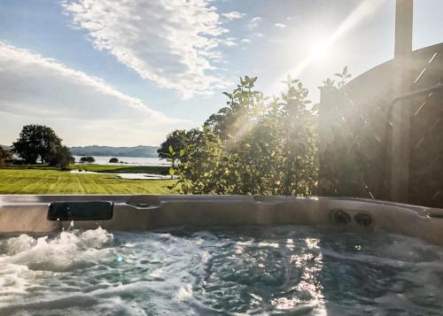 a jacuzzi tub with a view of the water at Loch Lomond Waterfront Luxury Lodges in Balmaha