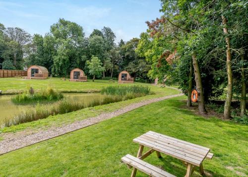 a wooden bench sitting in the grass next to a lake at Killerby Old Hall in Scarborough