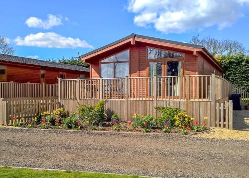 a house with a fence and flowers in front of it at Kings Lynn Holiday Park in King's Lynn