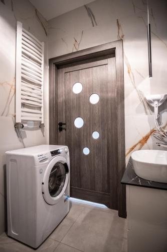 a washing machine in a bathroom with a wooden door at Azymut 48C in Stary Folwark