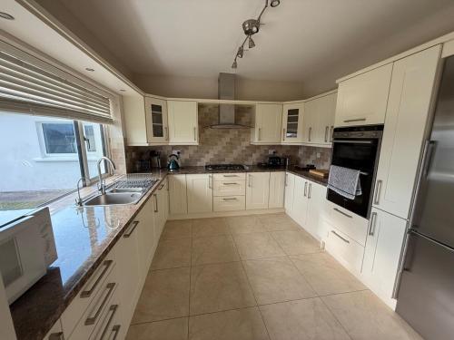 a kitchen with white cabinets and a sink at Carhan River Holiday Home - Cahersiveen in Cahersiveen