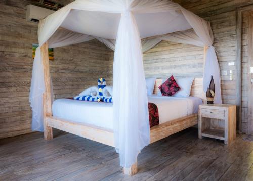a bedroom with a bed with a canopy at La Gautch Bungalow in Nusa Lembongan