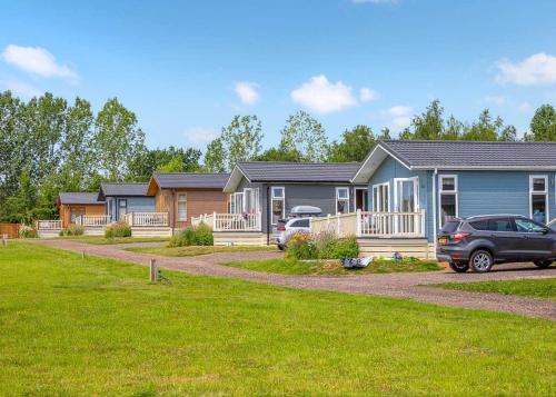 a row of houses with cars parked in a driveway at Otters Mead Boutique Lodges in Beetley