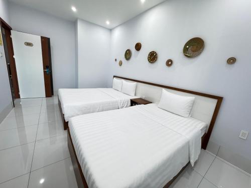 two beds in a room with white walls at An Nhiên Hotel in Tây Ninh