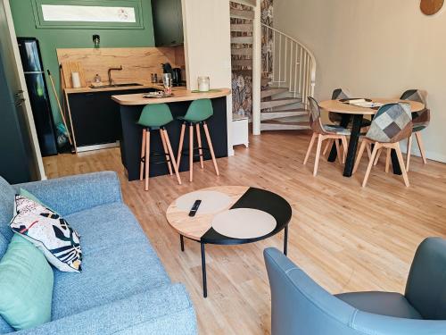 un salon avec un canapé bleu et des tables dans l'établissement Le cosy duplex centre, à Dinan