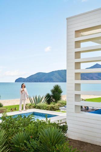 a woman standing next to a swimming pool next to the ocean at Sofitel Tamuda Bay Beach And Spa in M'diq