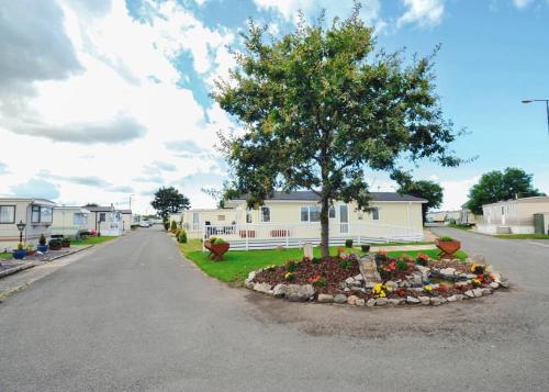 a tree in a flower bed in front of a house at Robin Hood Rhyl in Rhyl