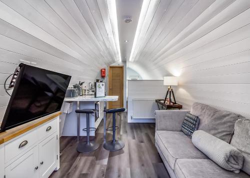 a living room with a couch and a flat screen tv at Peacock Lake Glamping in East Bridgford