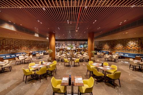 a dining room with tables and yellow chairs at Rixos Premium Dubai JBR in Dubai