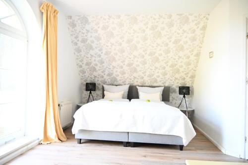 a bedroom with a bed with white sheets and floral wallpaper at Landsitzhotel und Seminarium Peterhof in Hodorf