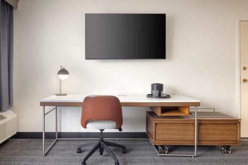 a desk with a chair and a television on a wall at Courtyard by Marriott Springfield Airport in Springfield