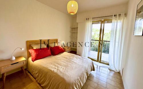 une chambre avec un lit avec des oreillers rouges et une fenêtre dans l'établissement Appartement Lugaro Paisible & charmant, à Calvi