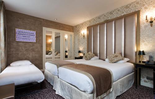 a hotel room with two beds and a fireplace at Hotel de L'Empereur by Malone in Paris