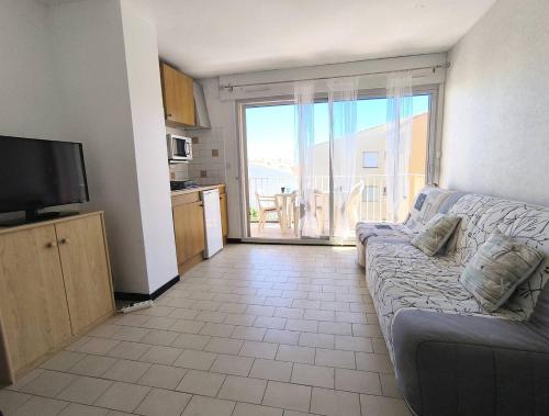 un salon avec un canapé et une grande fenêtre dans l'établissement 031 Palmeraie Studio avec parking plage du môle, au Cap d'Agde
