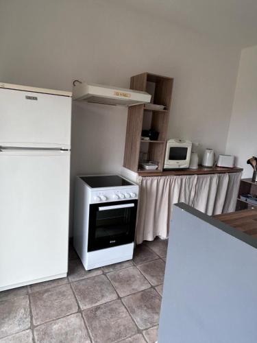 La cuisine est équipée d'une cuisinière blanche et d'un réfrigérateur. dans l'établissement Pietralba Un havre de paix entre mer et montagnes, à Pietralba